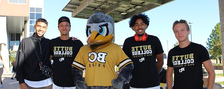 Student soccer players posing with mascot